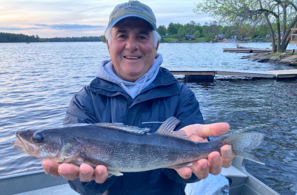 Fisherman (frank cecchini) extends his arms to display a rare blue walleye.