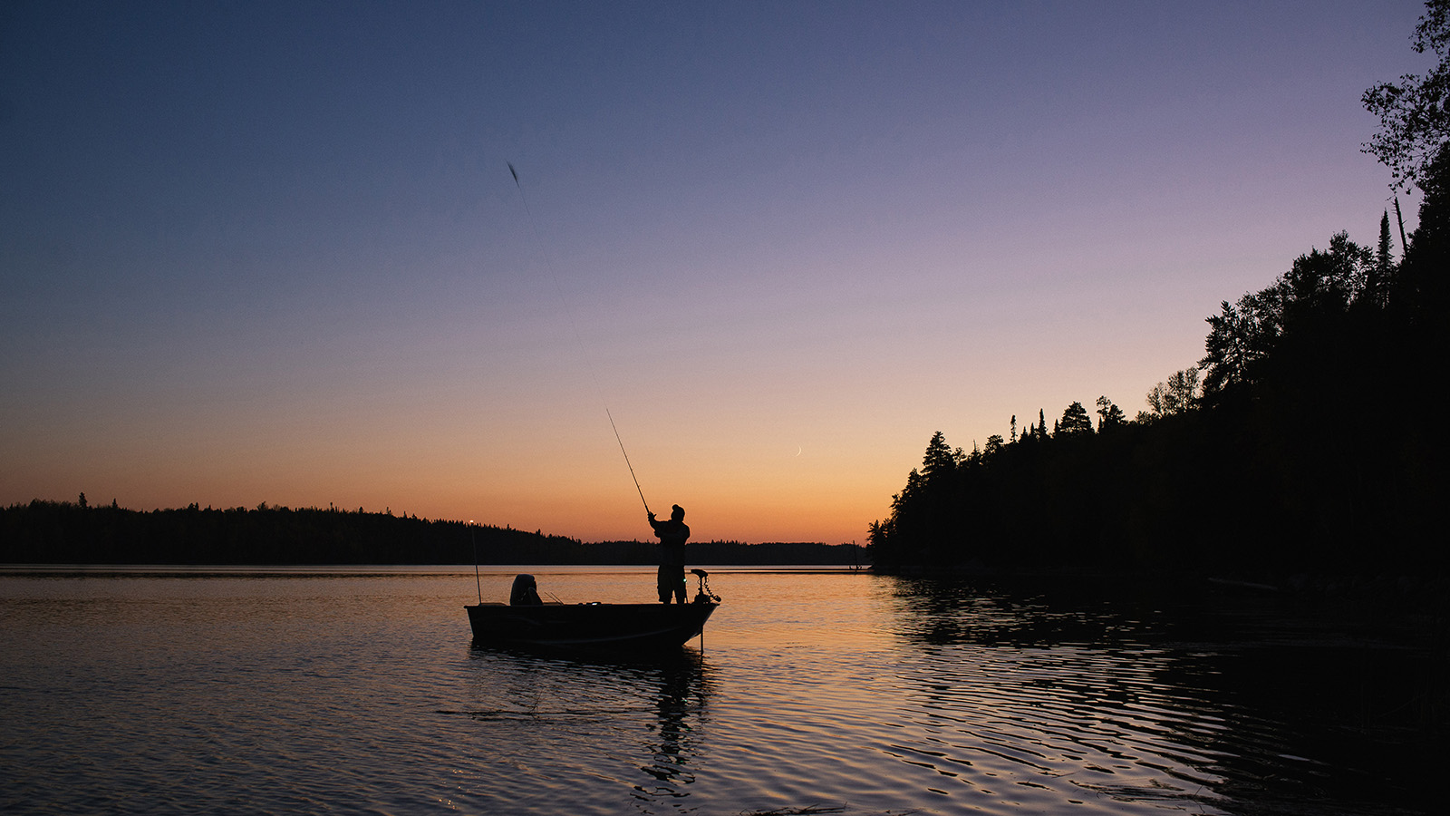 Angler fishing from boat at dusk